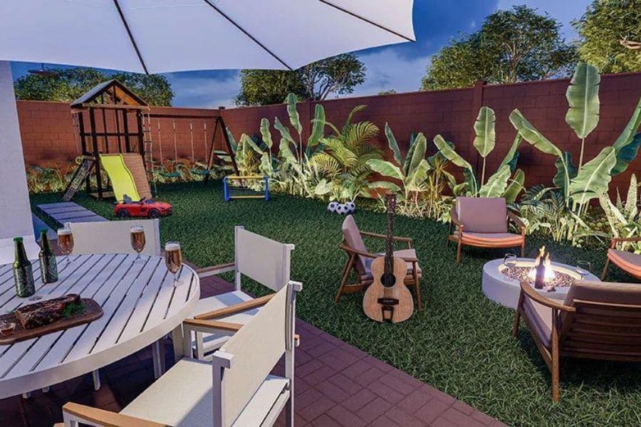 Imagem noturna de um quintal decorado e mobiliado de uma das Casas Le Jardin, com área de jantar, lareira externa, violão, playground infantil e iluminação aconchegante.
